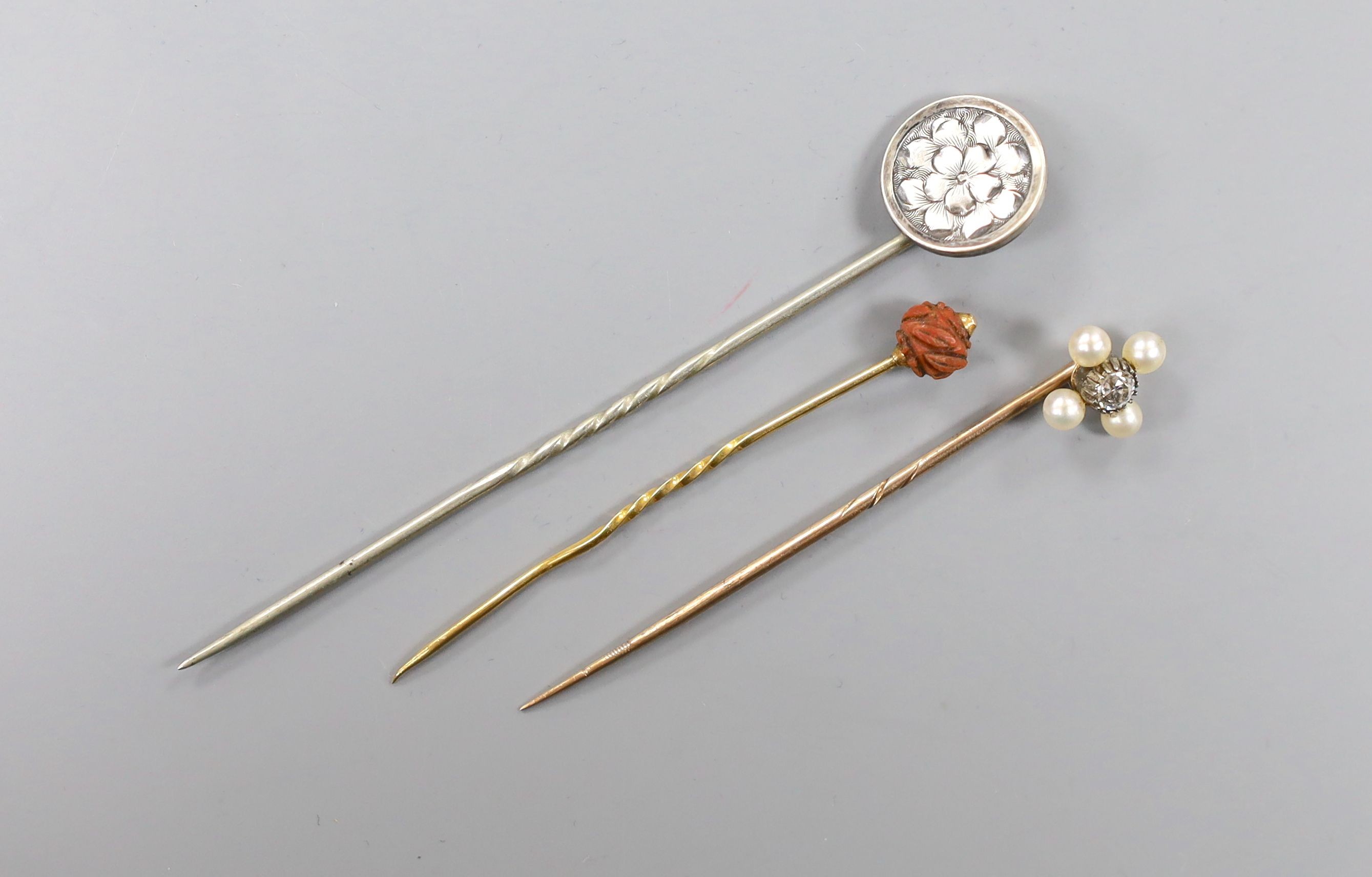 An Edwardian yellow metal, seed pearl and diamond set stick pin, 57mm and two other stick pins.